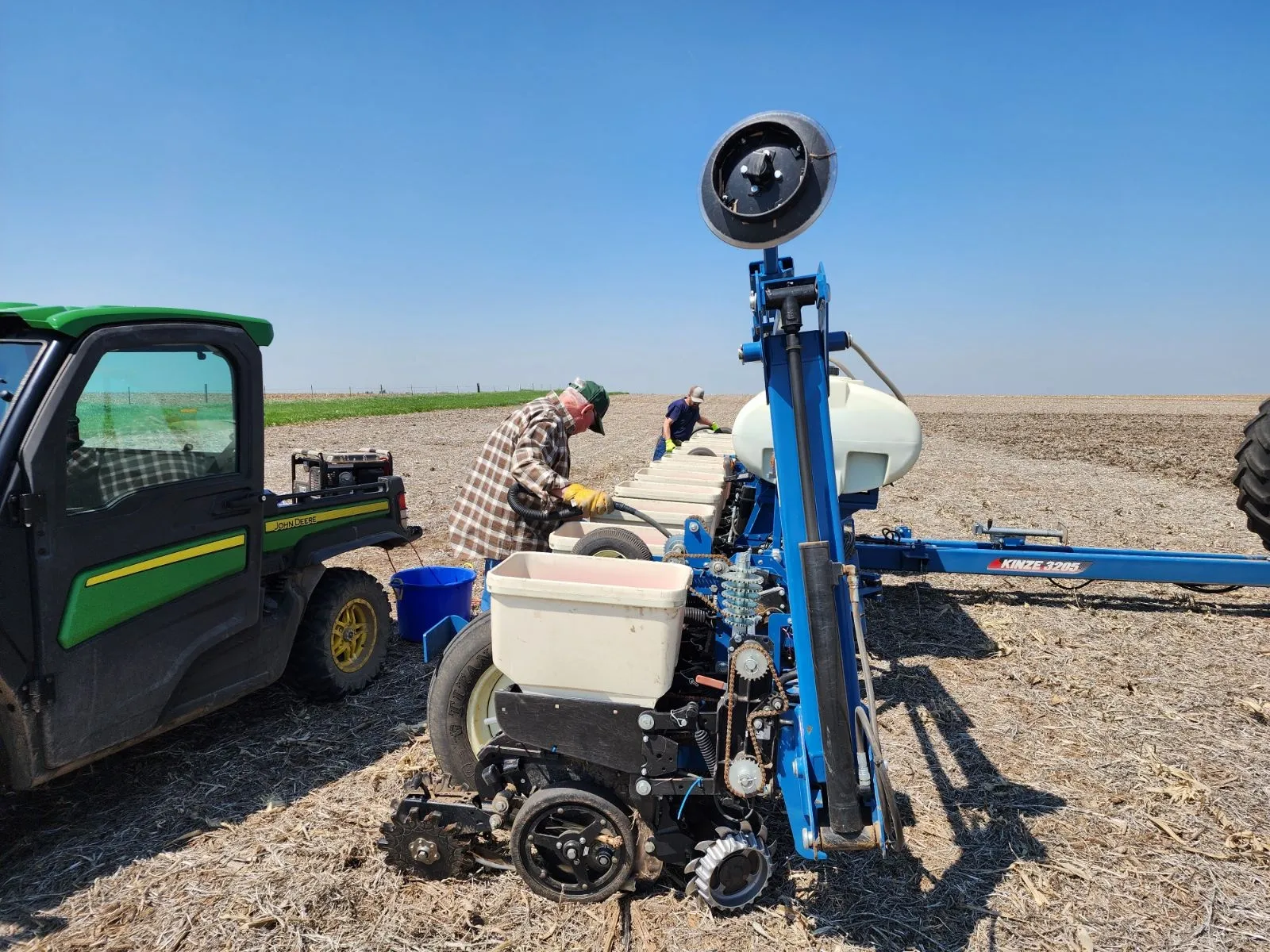 Farmers loading seed into a Kinze planter in the field